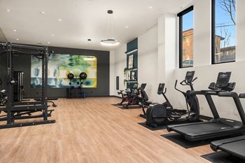a gym with treadmills and other exercise equipment on a wood floor